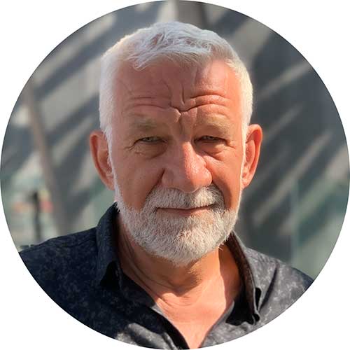 Älterer Mann mit kurzem weißen Haar und Bart im Sonnenlicht.