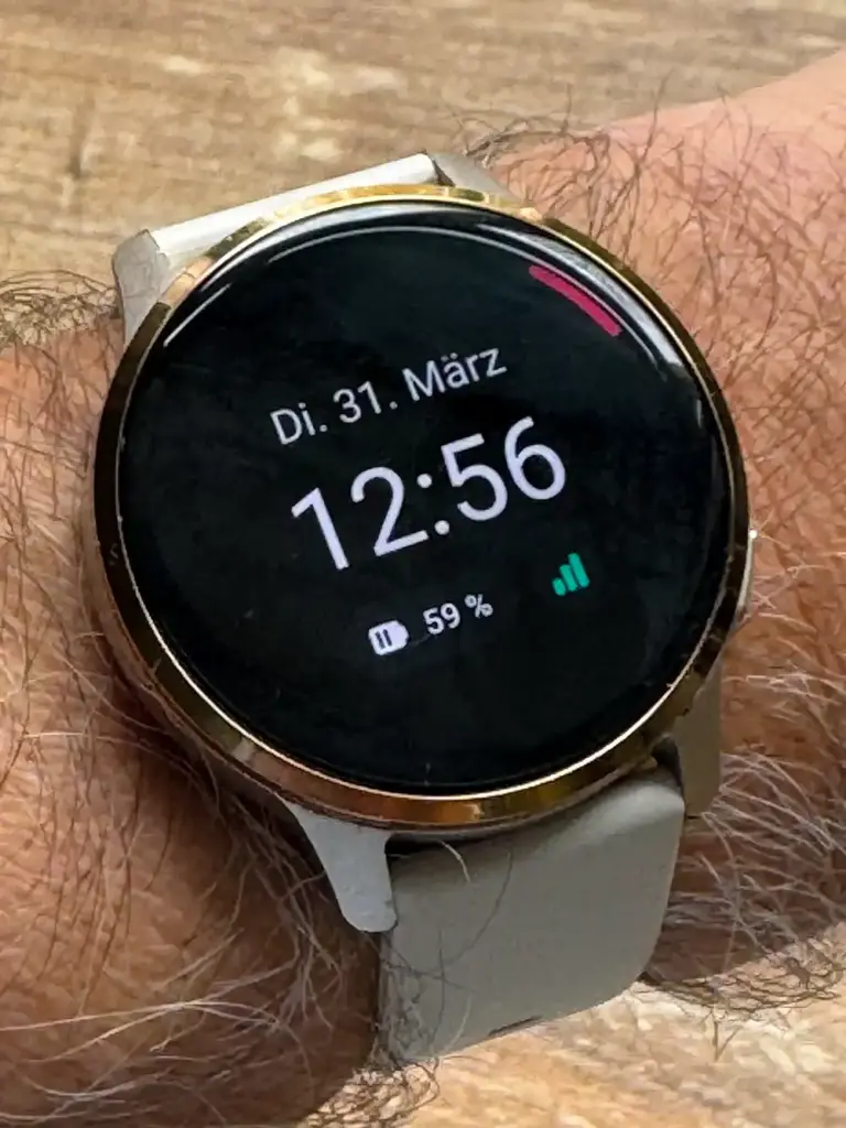 Eine Patronus Notfalluhr am Handgelenk zeigt das Datum, die Uhrzeit, den Batteriestand und die Verbindungsstärke auf schwarzem Untergrund an.