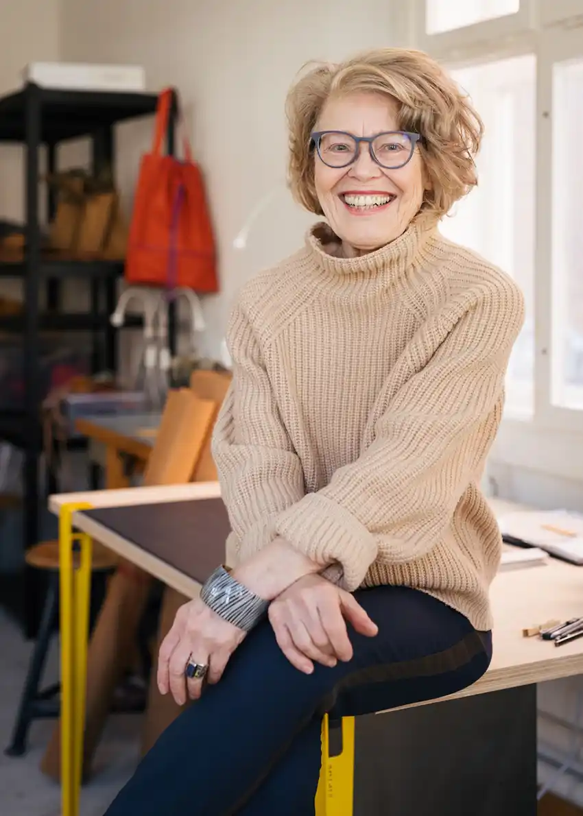 Elke-Jensen Eine ältere Frau mit Brille und beigefarbenem Pullover lächelt und verkörpert Senior Entrepreneurship in einem gut beleuchteten Raum.