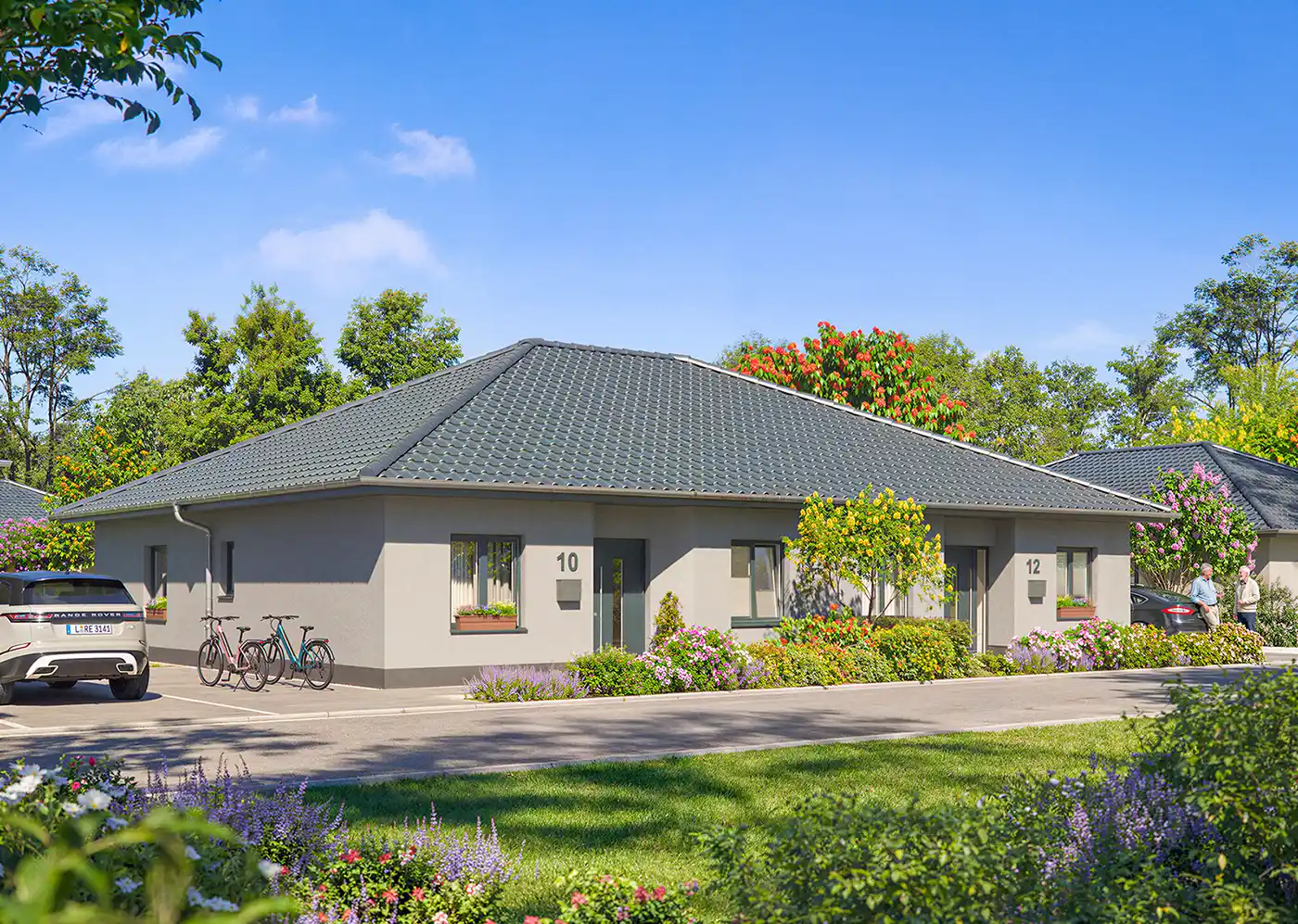 Seniorenwohnanlage-Grosspoesna-Haus-B-Strassenansicht Ein einstöckiges, modernes Doppelhaus mit grauem Dach, Gärten, abgestellten Fahrrädern und Autos an einem sonnigen Tag.